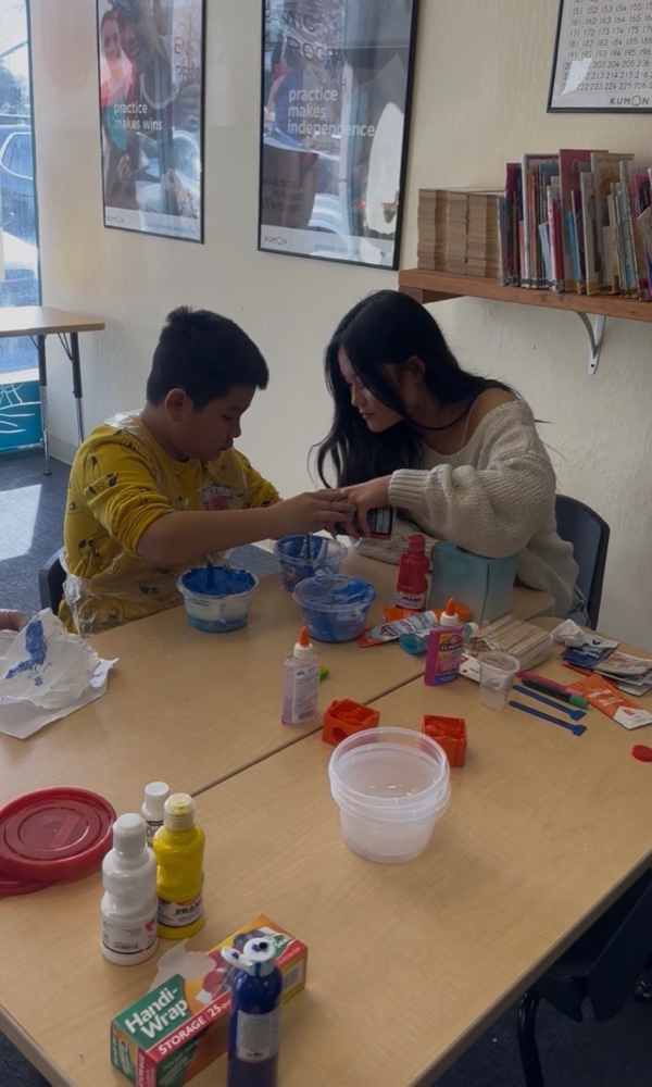 Two kids doing a craft activity together at a table