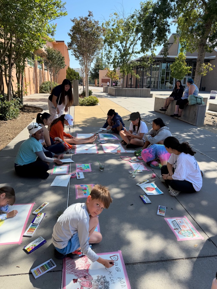Kids doing sidewalk chalk art together on a sunny day